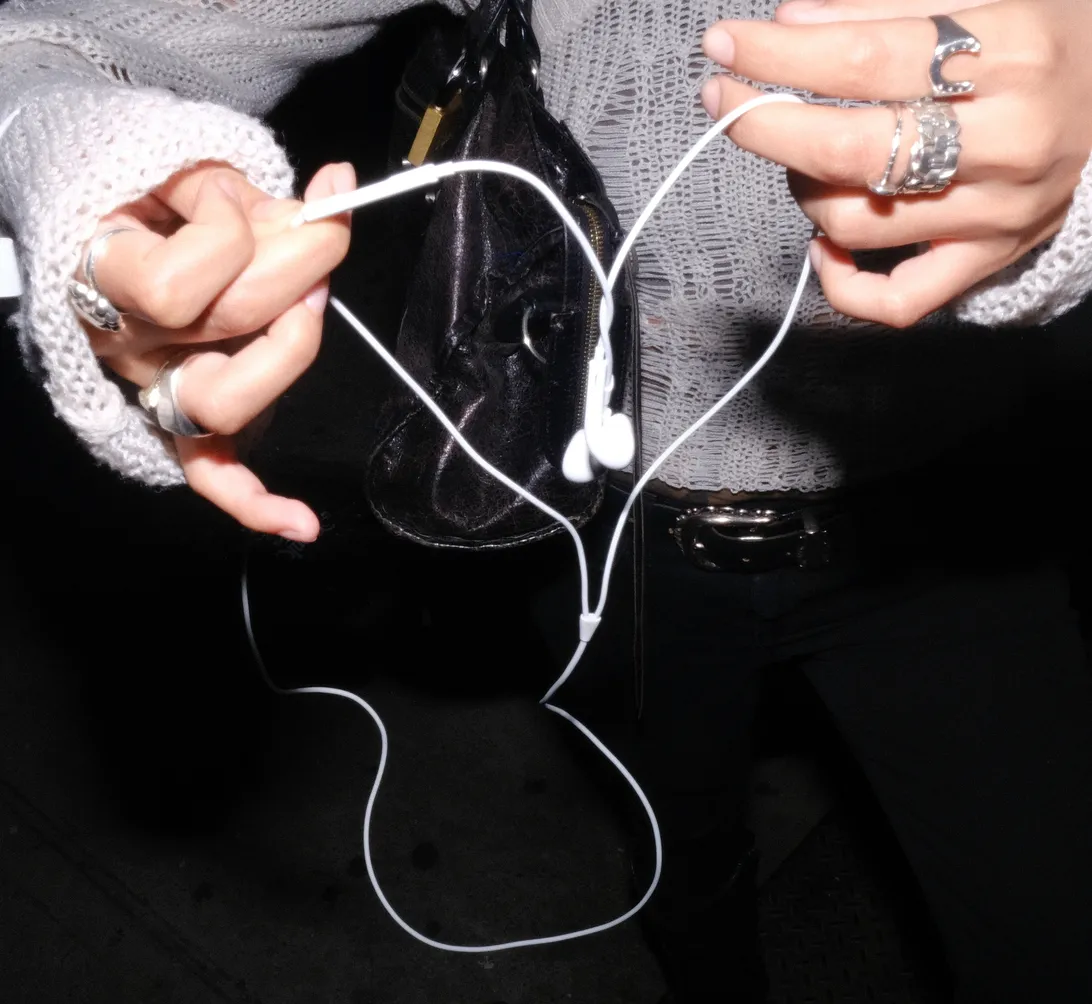 hands holding a tangled white earphone cable shaped like a heart